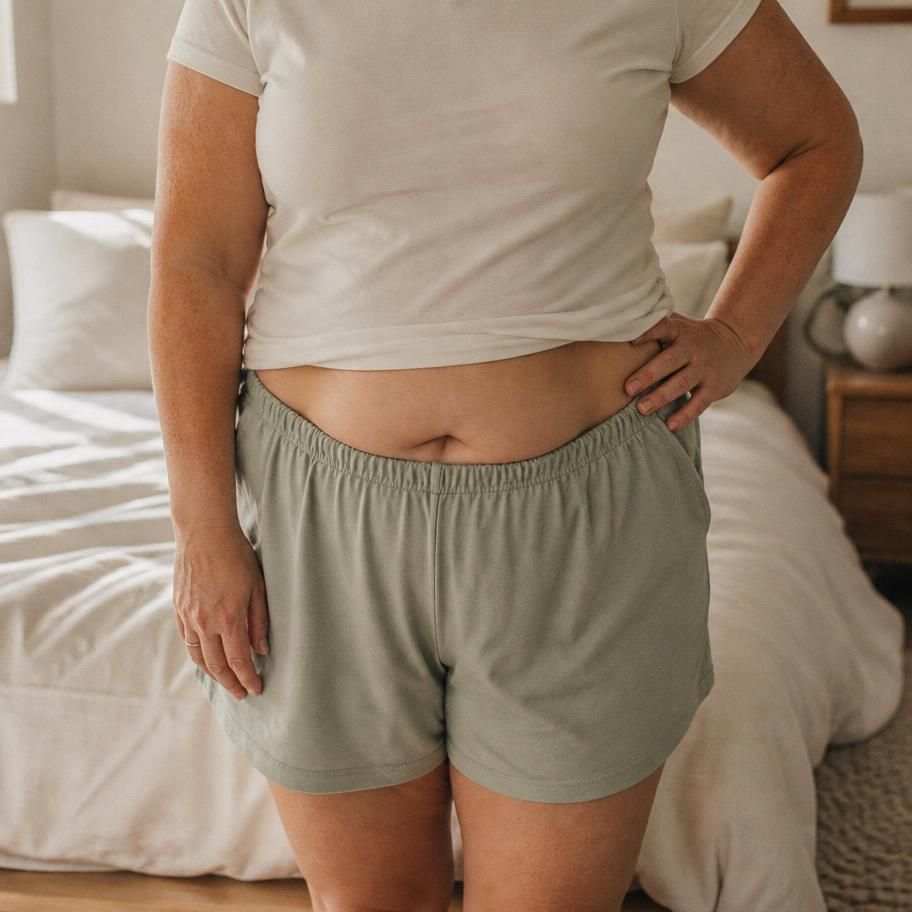 Close crop of a soft midsection with hands resting at the waist